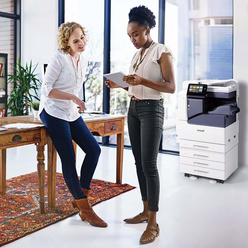 two people looking at a tablet next to a photocopier full scale